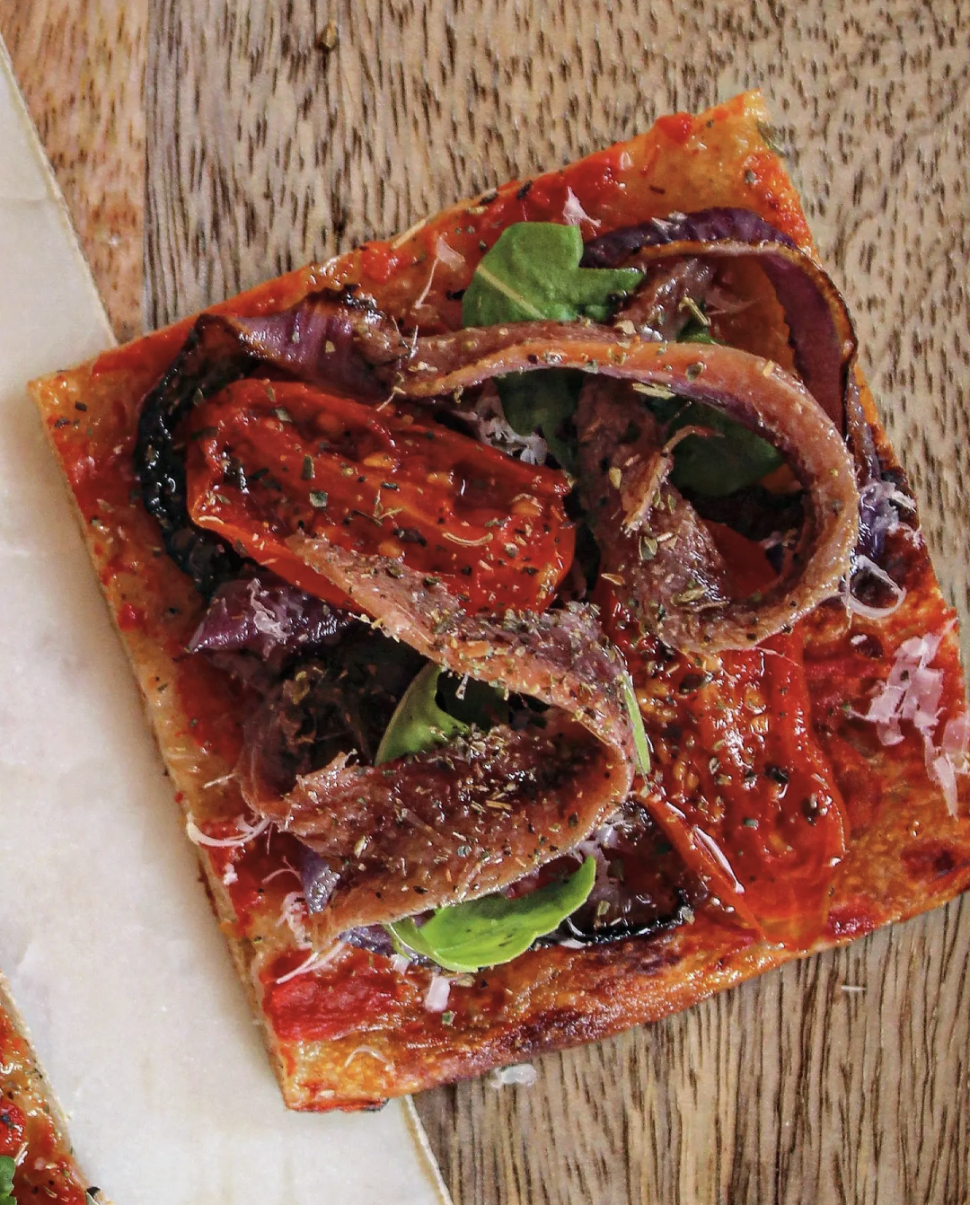 Pizza rossa con Alici del Mar Cantabrico cipolla di Tropea pomodorino confit pecorino e rucola